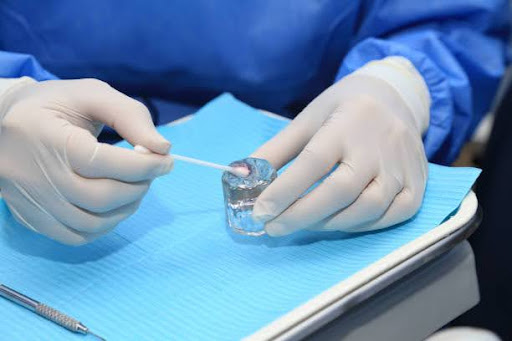 Doctor's hands holding swab and dipping it in fluoride
